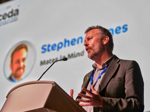 A presenter standing at a lectern delivering a speech as part of the Mates in Mind training and resources offering